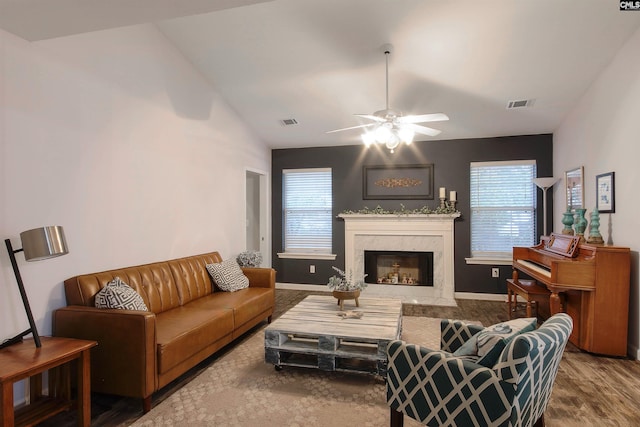 living room featuring vaulted ceiling, ceiling fan, a high end fireplace, and plenty of natural light