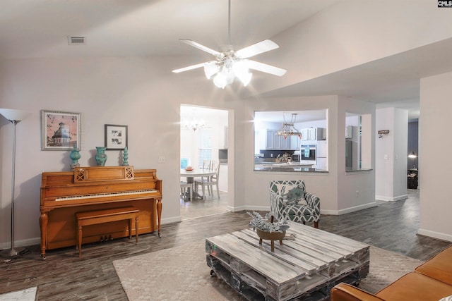 living room with ceiling fan with notable chandelier, vaulted ceiling, and dark hardwood / wood-style flooring