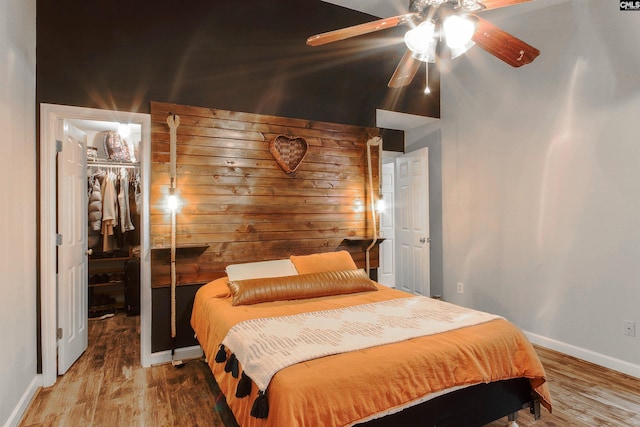 bedroom with a spacious closet, hardwood / wood-style floors, a closet, and ceiling fan