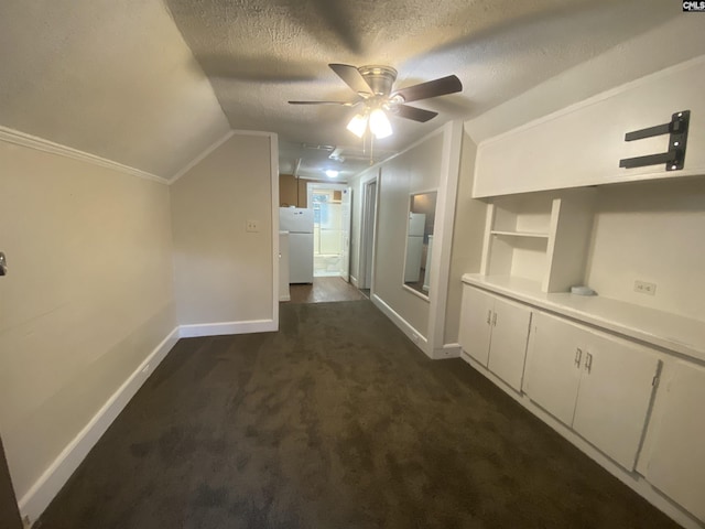 hallway with dark colored carpet, baseboards, lofted ceiling, and a textured ceiling