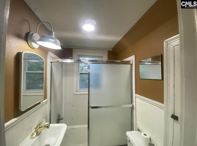 bathroom with a wainscoted wall, toilet, and tile walls