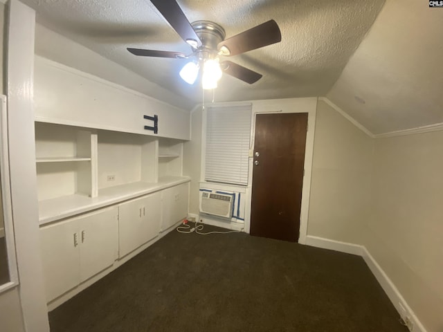 interior space featuring cooling unit, baseboards, vaulted ceiling, a textured ceiling, and dark carpet