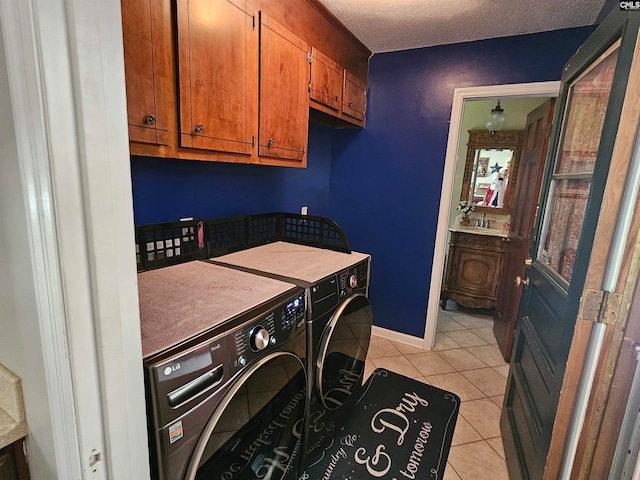 laundry room with cabinets, independent washer and dryer, a textured ceiling, light tile patterned floors, and sink