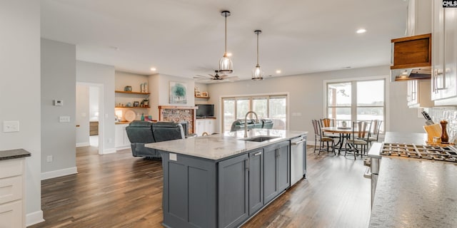 kitchen featuring light stone countertops, a stone fireplace, appliances with stainless steel finishes, sink, and gray cabinets