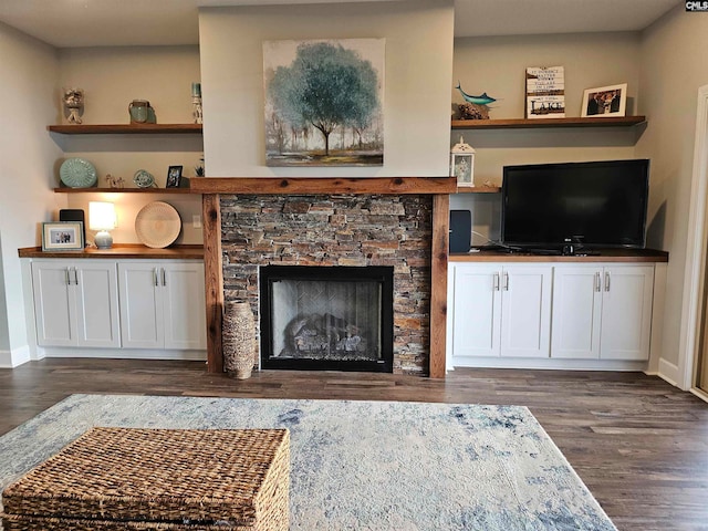 living room with dark wood-type flooring and a stone fireplace