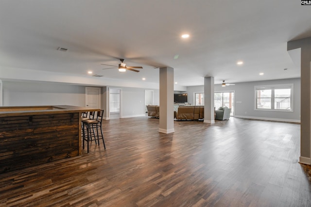 unfurnished living room with bar area, ceiling fan, and dark hardwood / wood-style flooring