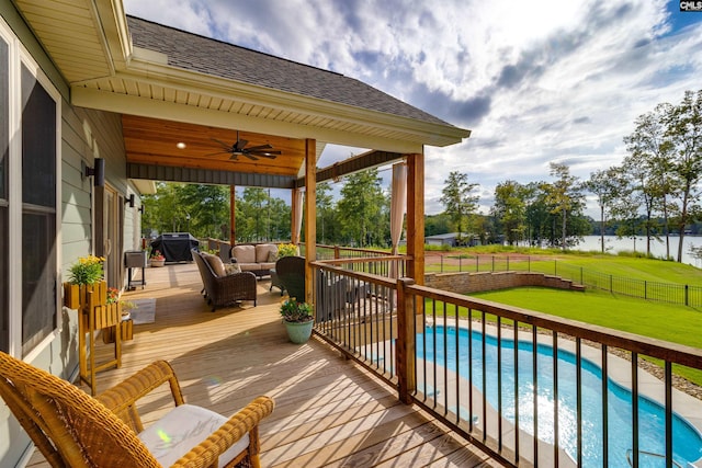 wooden deck featuring a water view, a fenced in pool, a lawn, ceiling fan, and an outdoor living space