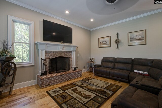 living room with light wood-type flooring, crown molding, and a brick fireplace