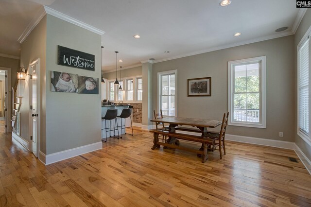 dining room with crown molding and light hardwood / wood-style floors