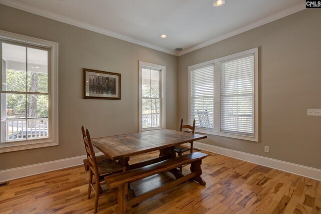 dining space featuring crown molding, light hardwood / wood-style flooring, and a wealth of natural light