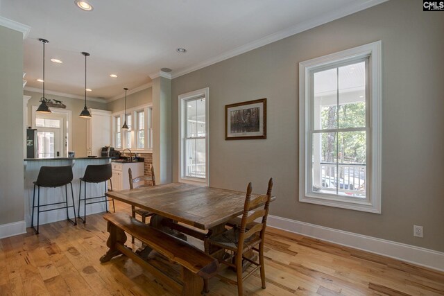 dining area featuring crown molding, sink, and light hardwood / wood-style floors