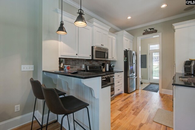 kitchen with a kitchen bar, light wood-type flooring, appliances with stainless steel finishes, and white cabinets