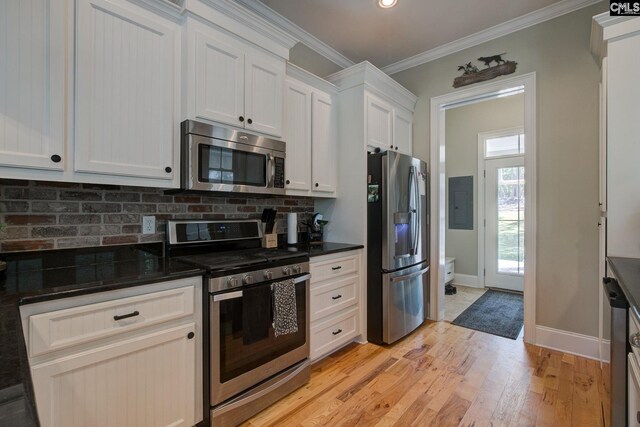 kitchen with light hardwood / wood-style flooring, ornamental molding, appliances with stainless steel finishes, and white cabinets