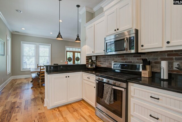 kitchen featuring decorative light fixtures, a wealth of natural light, stainless steel appliances, and light hardwood / wood-style floors