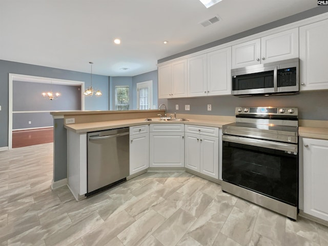 kitchen with decorative light fixtures, appliances with stainless steel finishes, a notable chandelier, sink, and kitchen peninsula