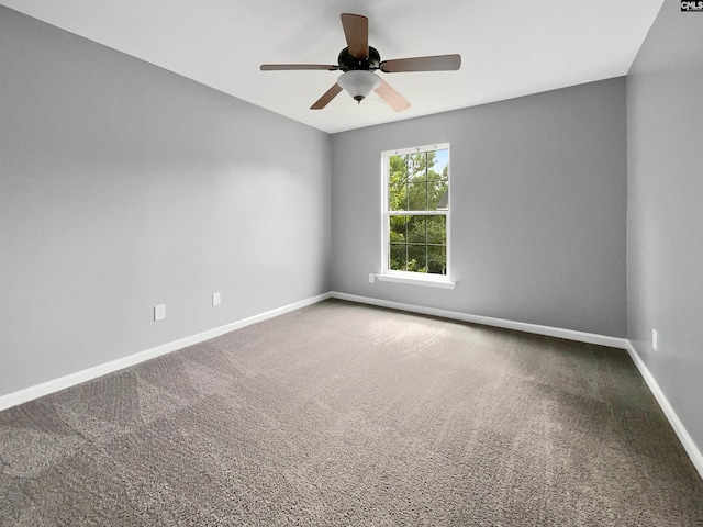 carpeted spare room featuring baseboards and ceiling fan