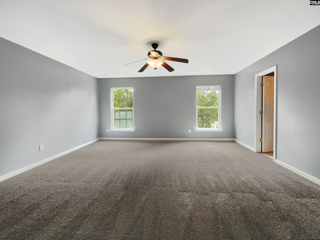 empty room featuring a ceiling fan, carpet, baseboards, and a wealth of natural light