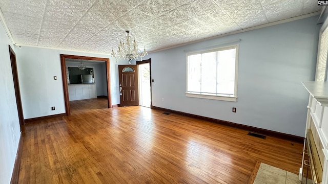 unfurnished living room featuring wood-type flooring, a chandelier, and crown molding