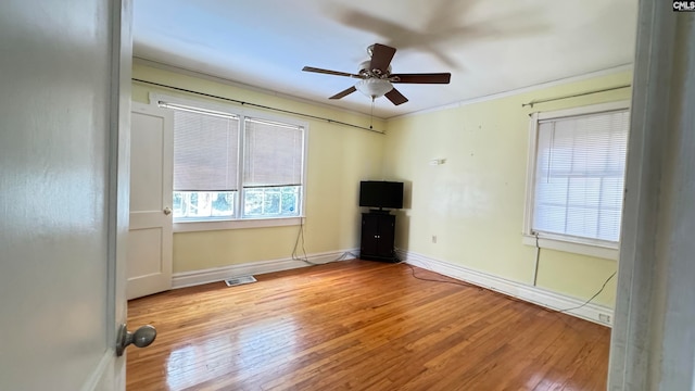 empty room with ceiling fan, crown molding, and wood-type flooring