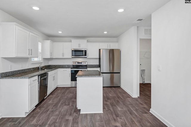 kitchen featuring white cabinets, appliances with stainless steel finishes, a kitchen island, and dark hardwood / wood-style flooring