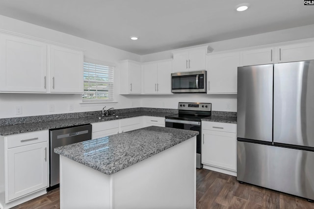 kitchen with dark hardwood / wood-style floors, appliances with stainless steel finishes, a center island, sink, and white cabinets