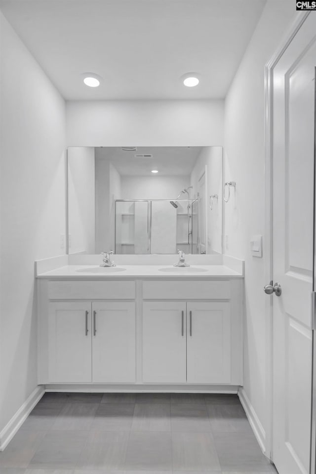 bathroom with a shower with door, vanity, and tile patterned flooring