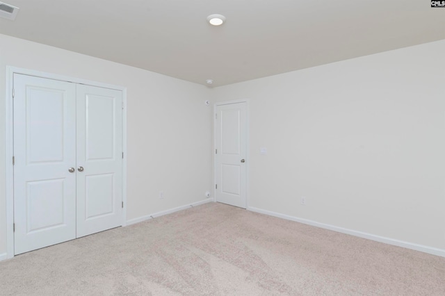 unfurnished bedroom featuring a closet and light carpet