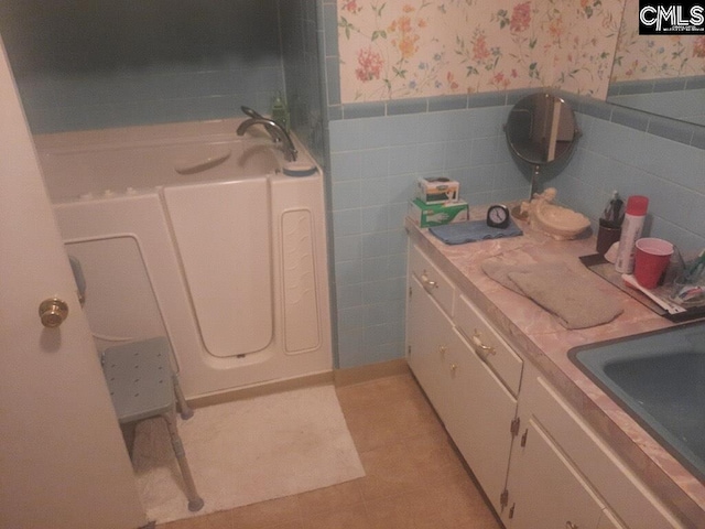 bathroom with a bathing tub, tile walls, sink, and tile patterned floors