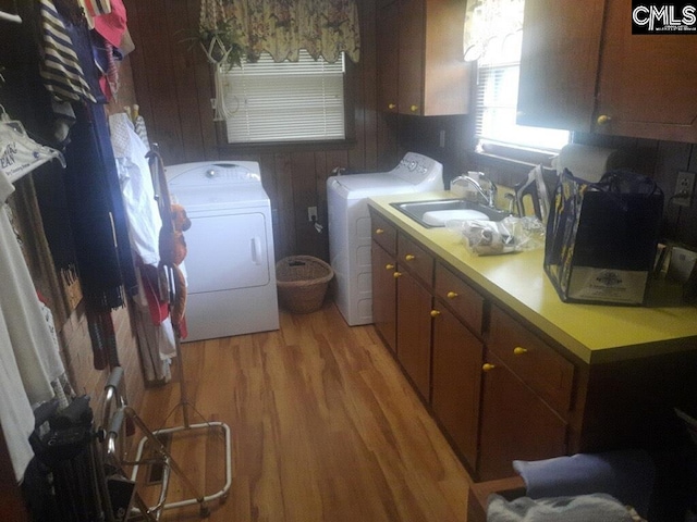 laundry area featuring light wood-type flooring, washer and dryer, cabinets, and sink