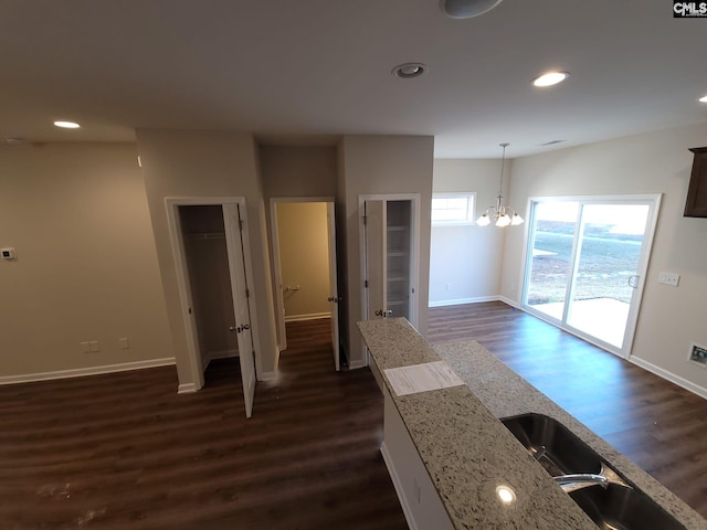 kitchen featuring an inviting chandelier, light stone counters, decorative light fixtures, and dark hardwood / wood-style flooring