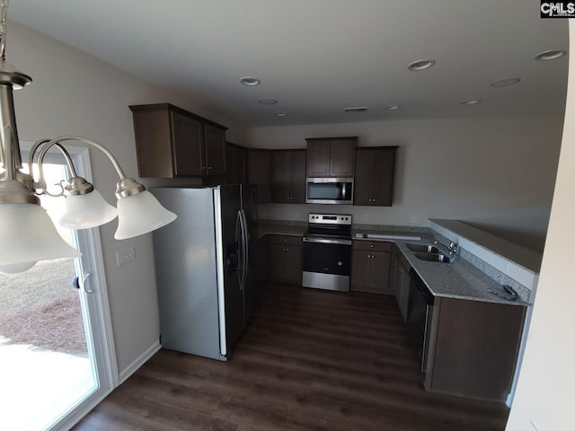 kitchen with dark stone countertops, a notable chandelier, stainless steel appliances, dark hardwood / wood-style flooring, and sink