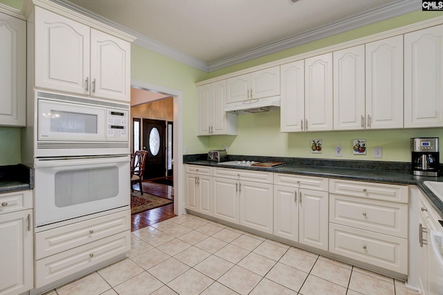 kitchen featuring white appliances, light tile patterned floors, and white cabinetry