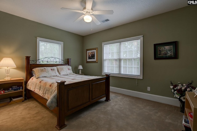 bedroom featuring multiple windows, a textured ceiling, ceiling fan, and carpet floors