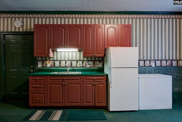 kitchen with a textured ceiling, dark carpet, sink, and white fridge