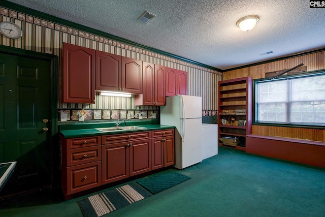 kitchen with a textured ceiling, white fridge, dark colored carpet, and sink