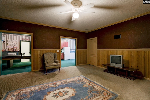 living area with carpet, a textured ceiling, ceiling fan, and wooden walls