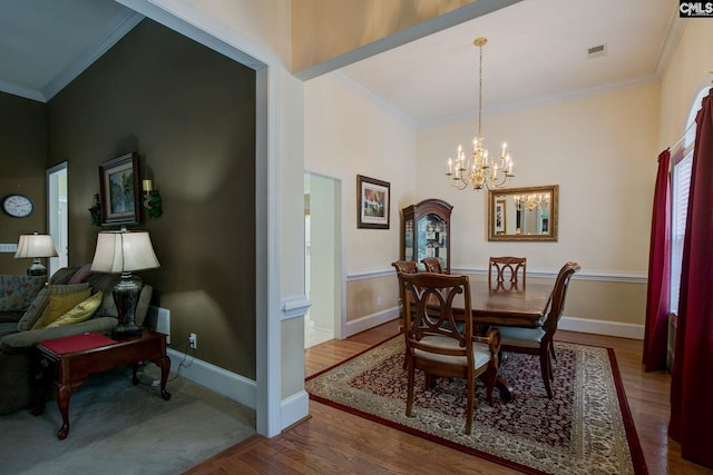 dining space featuring ornamental molding, wood-type flooring, and a notable chandelier