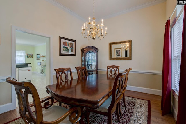 dining room with light wood-type flooring, an inviting chandelier, and ornamental molding