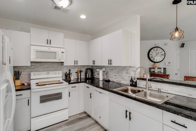 kitchen featuring white cabinetry, white appliances, visible vents, and a sink