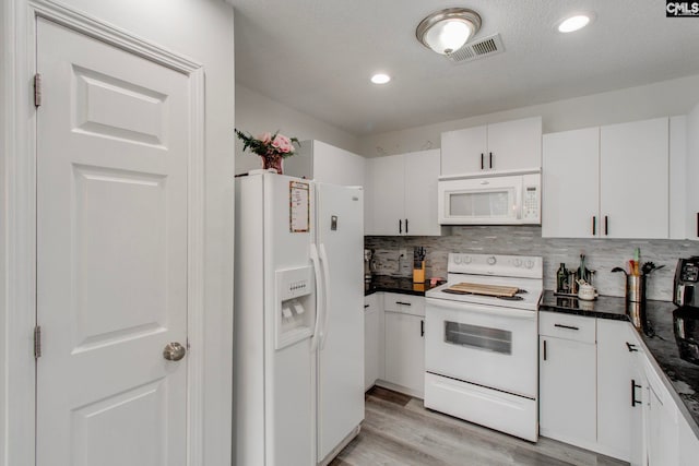 kitchen featuring dark countertops, backsplash, white appliances, and white cabinetry