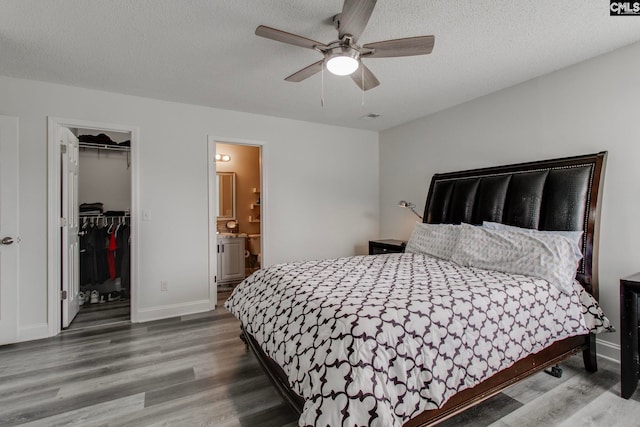 bedroom with a closet, a textured ceiling, wood finished floors, and a spacious closet