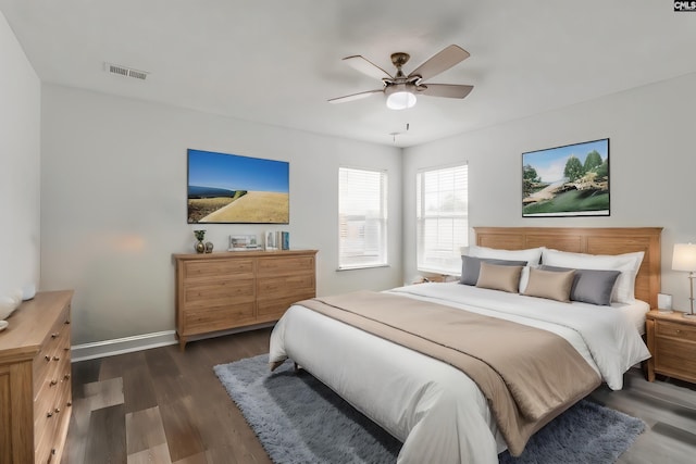 bedroom with visible vents, baseboards, dark wood finished floors, and a ceiling fan