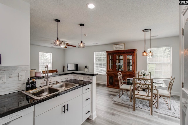 kitchen featuring a sink, dishwasher, dark countertops, ceiling fan with notable chandelier, and a wealth of natural light