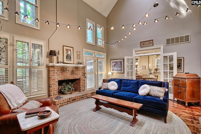 living room with a healthy amount of sunlight, high vaulted ceiling, parquet flooring, and a brick fireplace