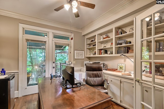 office area featuring built in desk, crown molding, french doors, ceiling fan, and dark wood-type flooring