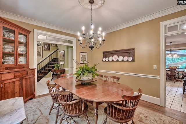 dining room with crown molding, light hardwood / wood-style flooring, and an inviting chandelier