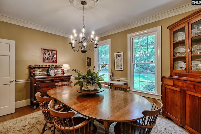 dining room with ornamental molding, an inviting chandelier, and light hardwood / wood-style floors