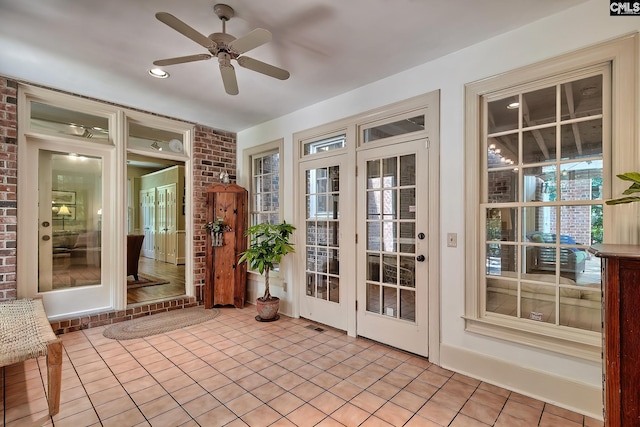 unfurnished sunroom with ceiling fan