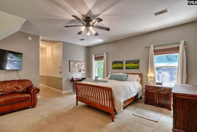 bedroom with multiple windows, ceiling fan, and light carpet