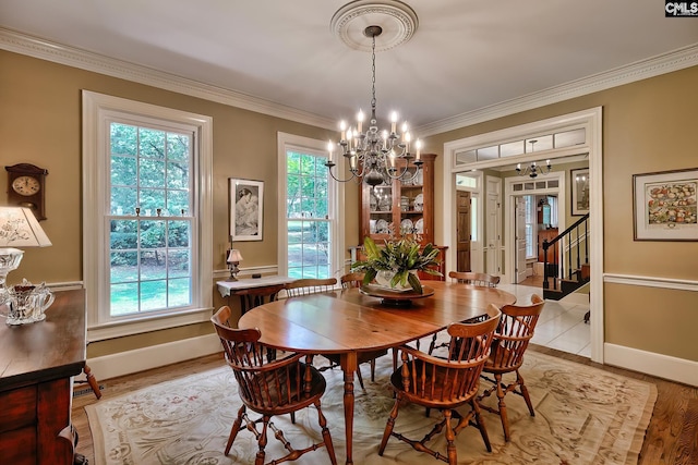 dining space featuring light wood-type flooring, ornamental molding, and an inviting chandelier